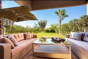 a patio with two couches and an umbrella at Appartement de luxe avec jardin privé in Marrakesh
