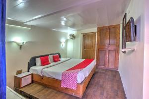 a bedroom with a bed with red pillows at Hotel Shishamaati in Kulu