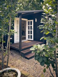 una casita azul con porche de madera en Bundanoon Garden Retreat, en Bundanoon
