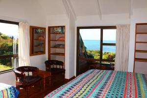 a bedroom with a bed and a view of the ocean at Shambhala Cabins in Onekaka