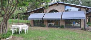 a table and chairs in front of a building at La Calma, casa frente al río, gran parque y pileta in Villa Icho Cruz