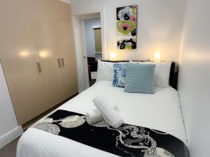 1 dormitorio con 1 cama blanca grande con almohadas azules en East Melbourne unit with courtyard, en Melbourne