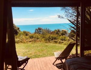 a room with a view of the ocean from a porch at Shambhala Cabins in Onekaka