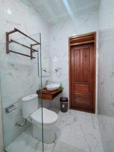 een witte badkamer met een toilet en een wastafel bij Spring Hill Hotel Ruteng in Ruteng