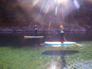 dos personas están en tablas de paddle en el agua en KAMENOI HOTEL Kochi, en Ino