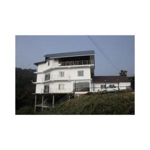 un grand bâtiment blanc au sommet d'une colline dans l'établissement Blossom Valley Cottage, à Munnar