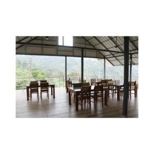 une salle à manger avec tables et chaises et une grande fenêtre dans l'établissement Blossom Valley Cottage, à Munnar