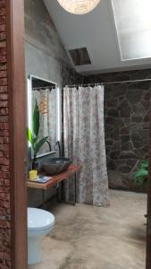 a bathroom with a toilet and a shower curtain at Villa di Bukit Lawang: LocalDailyLife, near Jungle in Bukit Lawang