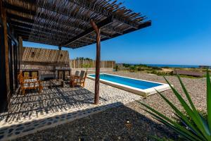 a patio with a table and chairs and a swimming pool at Macondo, casa de playa en Vichayito by WiroHouse in Vichayito