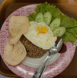 a plate of food with an egg and rice and vegetables at Brahmastra Bali villa in Kubupenlokan