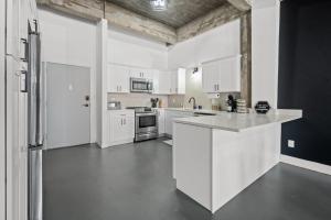 a large white kitchen with white cabinets and appliances at Charming Boho Loft on Historic Morris Ave in Birmingham