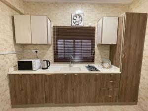 a kitchen with a sink and a microwave at شقه حديثه بالقرب من المسجد النبوي غرفتين وصاله ومطبخ وحمام تتسع لخمس اشخاص in Al Madinah