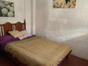 Cama en habitación con pared de ladrillo blanco en Casa amarilla PH depa 2dorm 3er piso, en Punta Hermosa