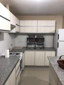 a kitchen with white cabinets and a stove top oven at Reserva Tajamar in Alta Gracia