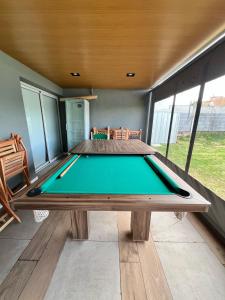 a pool table in the middle of a room with windows at Reserva Tajamar in Alta Gracia