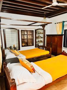 two beds in a room with yellow sheets at Srivilas in Pudunagaram