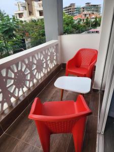 twee rode stoelen en een witte tafel op een balkon bij Kezmo Siloam Paradise in Mombasa