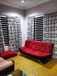 a living room with a red couch in front of windows at De'Lakeside musslim's homestay in Raub