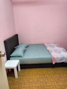 Cama en habitación con pared de color rosa en De'Lakeside musslim's homestay en Raub