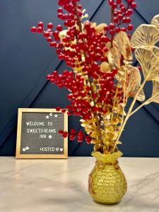 a vase with red flowers in it next to a sign at NEW Cozy Menjalara 5mins to DesaParkCity 2Rooms in Kuala Lumpur