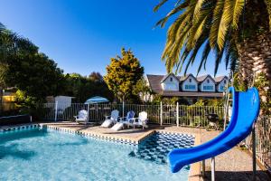 - une piscine avec toboggan en face d'une maison dans l'établissement ASURE Colonial Lodge Motel, à Napier