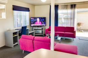 ein Wohnzimmer mit rosa Möbeln und einem Flachbild-TV in der Unterkunft ASURE Colonial Lodge Motel in Napier