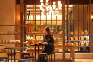 una mujer sentada en una mesa en una panadería en NOHGA HOTEL KIYOMIZU KYOTO, en Kioto