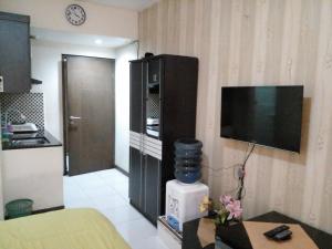 a living room with a television and a table with flowers at GREENROOM Apartemen Bogor Valley in Kalibata 1