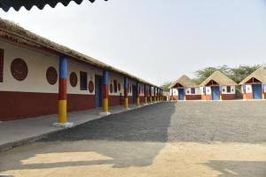 a row of houses with thatched roofs and a driveway at Rann Kutch Resort in Dhordo