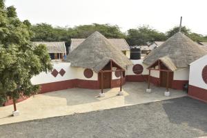 a group of houses with thatched roofs and a parking lot at Rann Kutch Resort in Dhordo