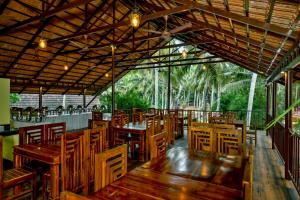 a restaurant with wooden tables and chairs and palm trees at GoGo Land Resort & Adventurous Sports in Pūvār