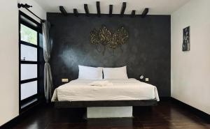 1 dormitorio con 1 cama con pared negra en Prana Hotel en Siem Reap
