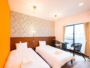 two beds in a room with a table and chairs at ランズコンドホテル宮古島 in Miyakojima