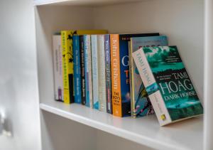 a row of books sitting on a shelf at Gartree Cottage in Fowey