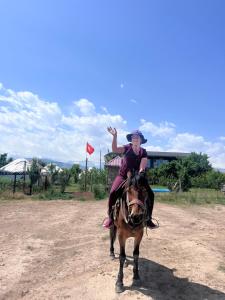a woman riding on the back of a horse at Guest house and yurt camp "Aktan" in Bokonbayevo