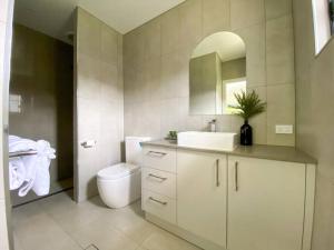 W łazience znajduje się umywalka, toaleta i lustro. w obiekcie The Olive Abode - Atherton w mieście Atherton