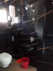 uma casa de banho com um WC e uma parede de azulejos pretos em Gajananstay Beach facing Rooms Indians only em Gokarn