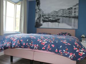 uma cama com um edredão azul com flores em Renovated farm with heated pool em Laakdal