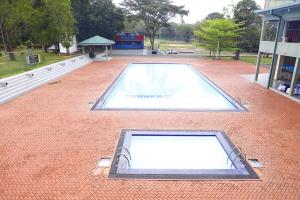 a swimming pool on a brick ground with a building at Gunners Club in Minneriya