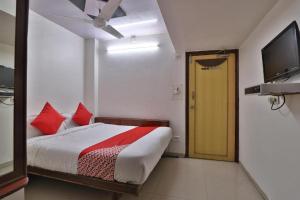 a bedroom with a bed and a television and a door at Hotel Maninagar Residency in Ahmedabad