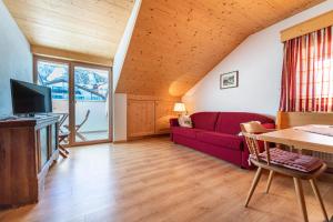 a living room with a red couch and a tv at Week End Senoner in Selva di Val Gardena