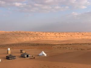 Thousand Stars Desert Camp في Badīyah: مجموعة من الخيام وخيمة بيضاء في الصحراء
