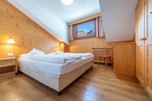 een slaapkamer met een groot bed in een houten kamer bij Week End Senoner in Selva di Val Gardena