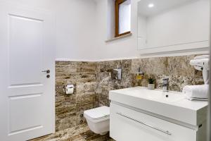 a white bathroom with a toilet and a sink at Sika Royal Central Apartment in Arad