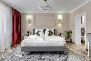 um quarto com uma grande cama branca e cortinas vermelhas em Sika Royal Central Apartment em Arad