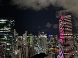 Pool Rooftop Luxury loft Miami Downtown, Brickell في ميامي: أفق المدينة في الليل مع مبنى طويل