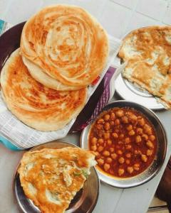 four plates of food with pancakes and beans on a table at Shelton House in Karachi