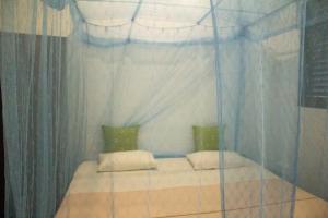a bedroom with a canopy bed with two pillows at Muru's Place in Dickwella