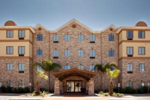 Staybridge Suites Corpus Christi, an IHG Hotel في كوربوس كريستي: مبنى من الطوب كبير مع أشجار النخيل في الأمام