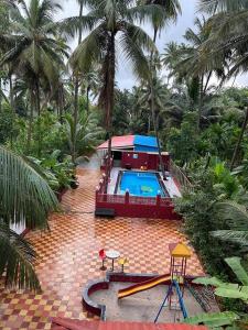 un complejo con piscina y palmeras en Srushti Sea Villa Resort, en Diveagar